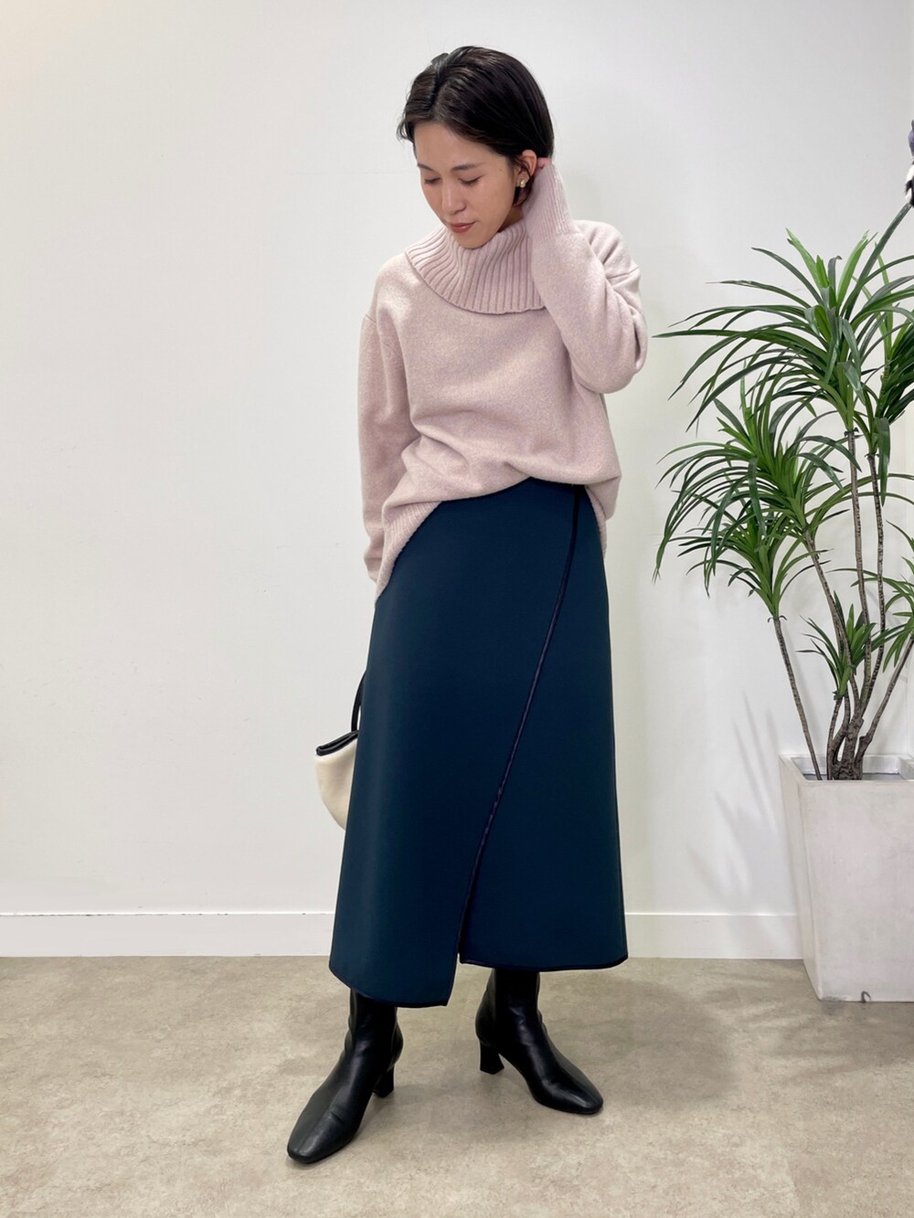 ブラック系のブーツ、パープル系のニット/セーター、ホワイト系のトートバッグを着用したレディースの冬コーディネートの2枚目の写真