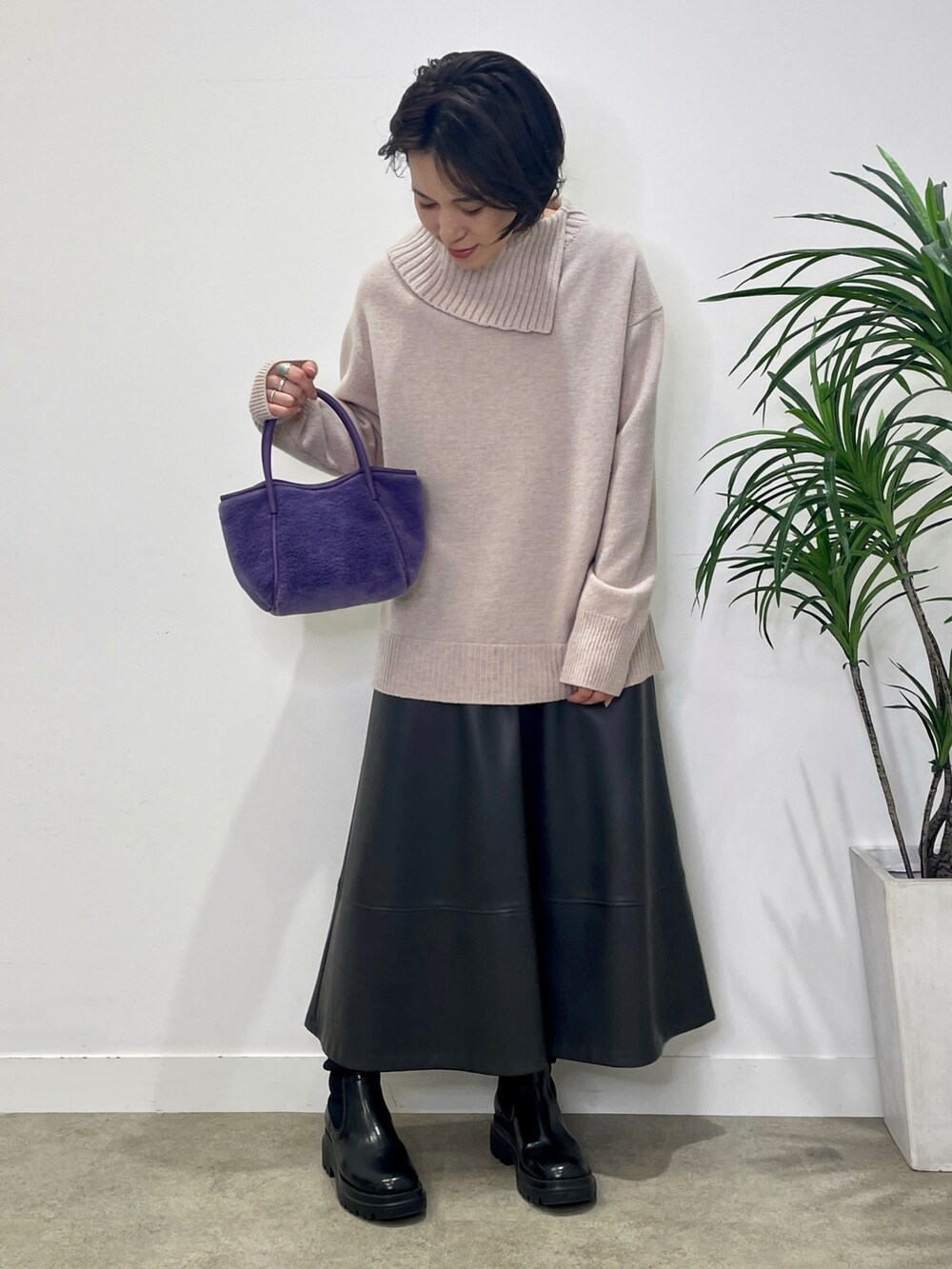 パープル系のニット/セーター、グレー系のステンカラーコート、グレー系のスカートを着用したレディースの冬コーディネートの4枚目の写真