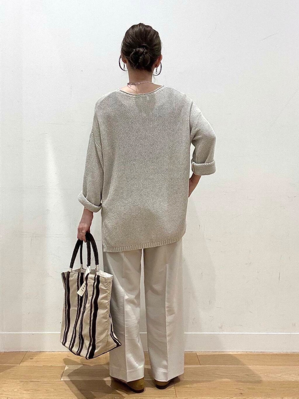 ベージュ系のニット/セーター、イエロー系のサンダル、ブラウン系のトートバッグを着用したレディースの春コーディネートの4枚目の写真