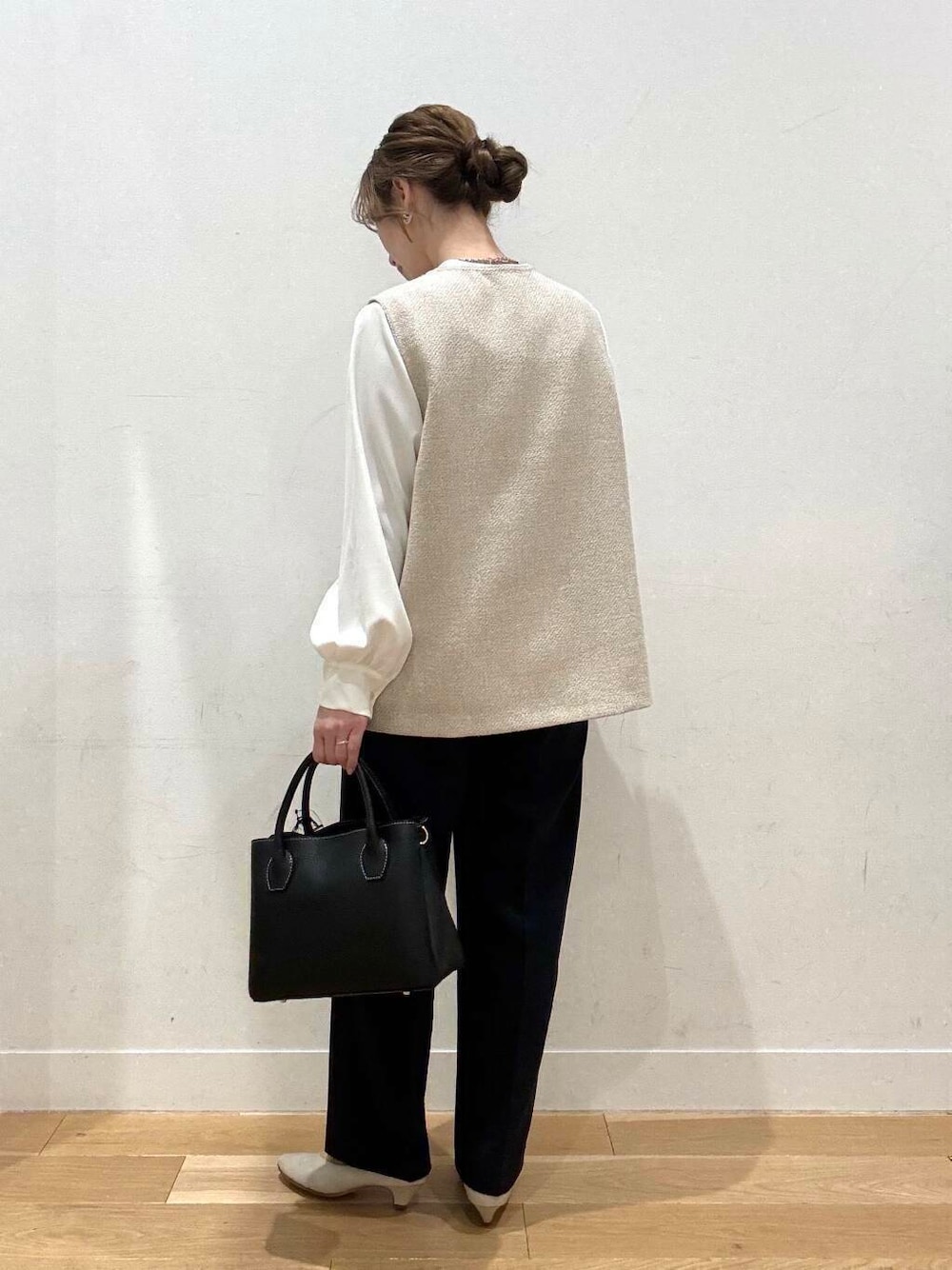 ブラック系のショルダーバッグ、ベージュ系のベスト、グレー系のスーツジャケットを着用したレディースの春コーディネートの2枚目の写真