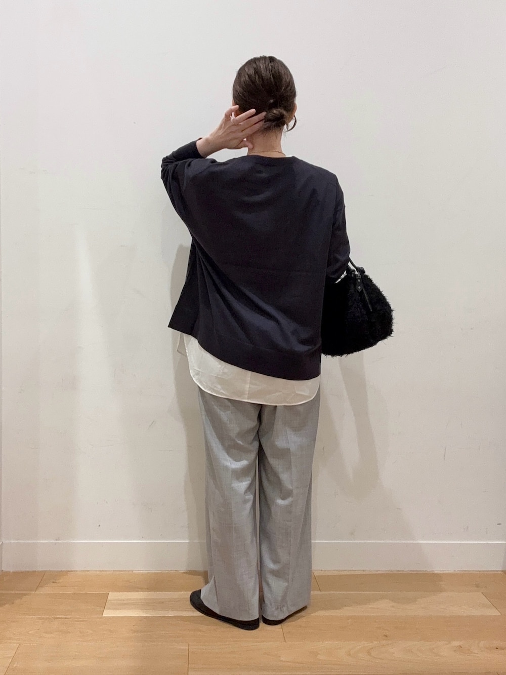 グレー系のニット/セーター、ホワイト系のダウンジャケット/コート、ブラック系のハンドバッグを着用したレディースの秋コーディネートの2枚目の写真