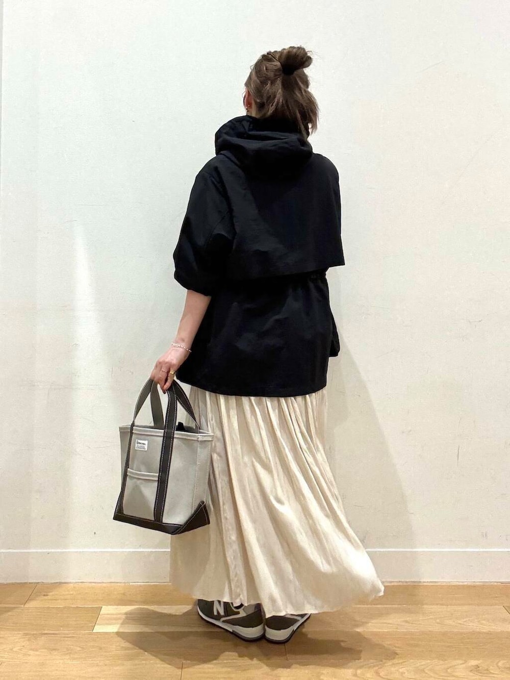 ブラック系のマウンテンパーカー、ホワイト系のスカート、グレー系のスウェットを着用したレディースの春コーディネートの2枚目の写真