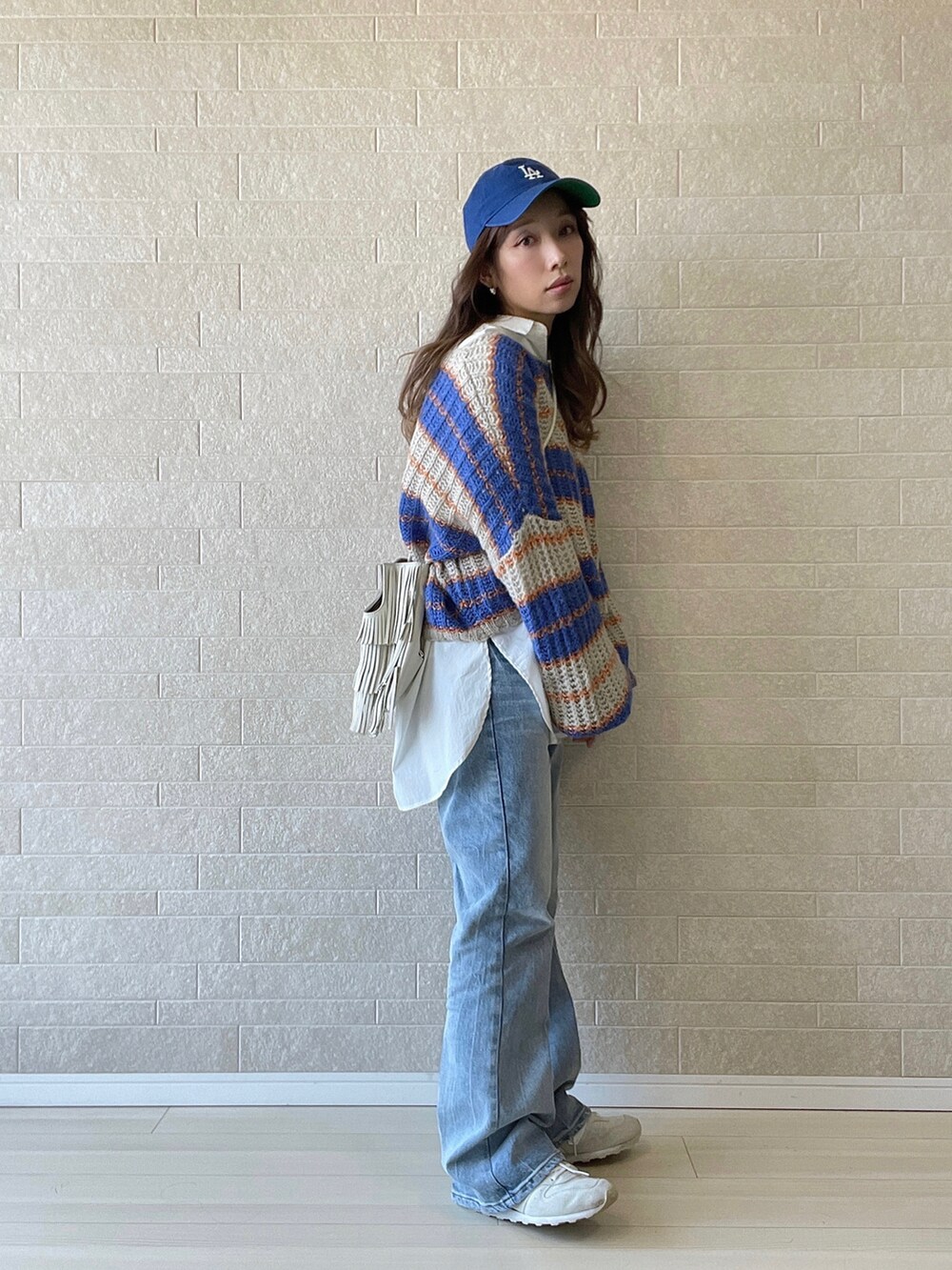 ブルー系のデニムパンツ、ホワイト系のシャツ/ブラウス、ホワイト系のスニーカーを着用したレディースの秋コーディネートの2枚目の写真