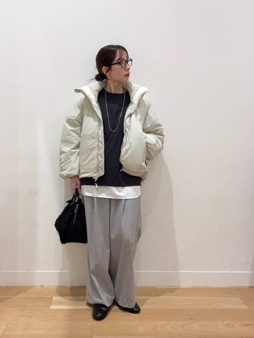 グレー系のニット/セーター、ホワイト系のダウンジャケット/コート、ブラック系のハンドバッグを着用したレディースの秋コーディネートの5枚目の写真