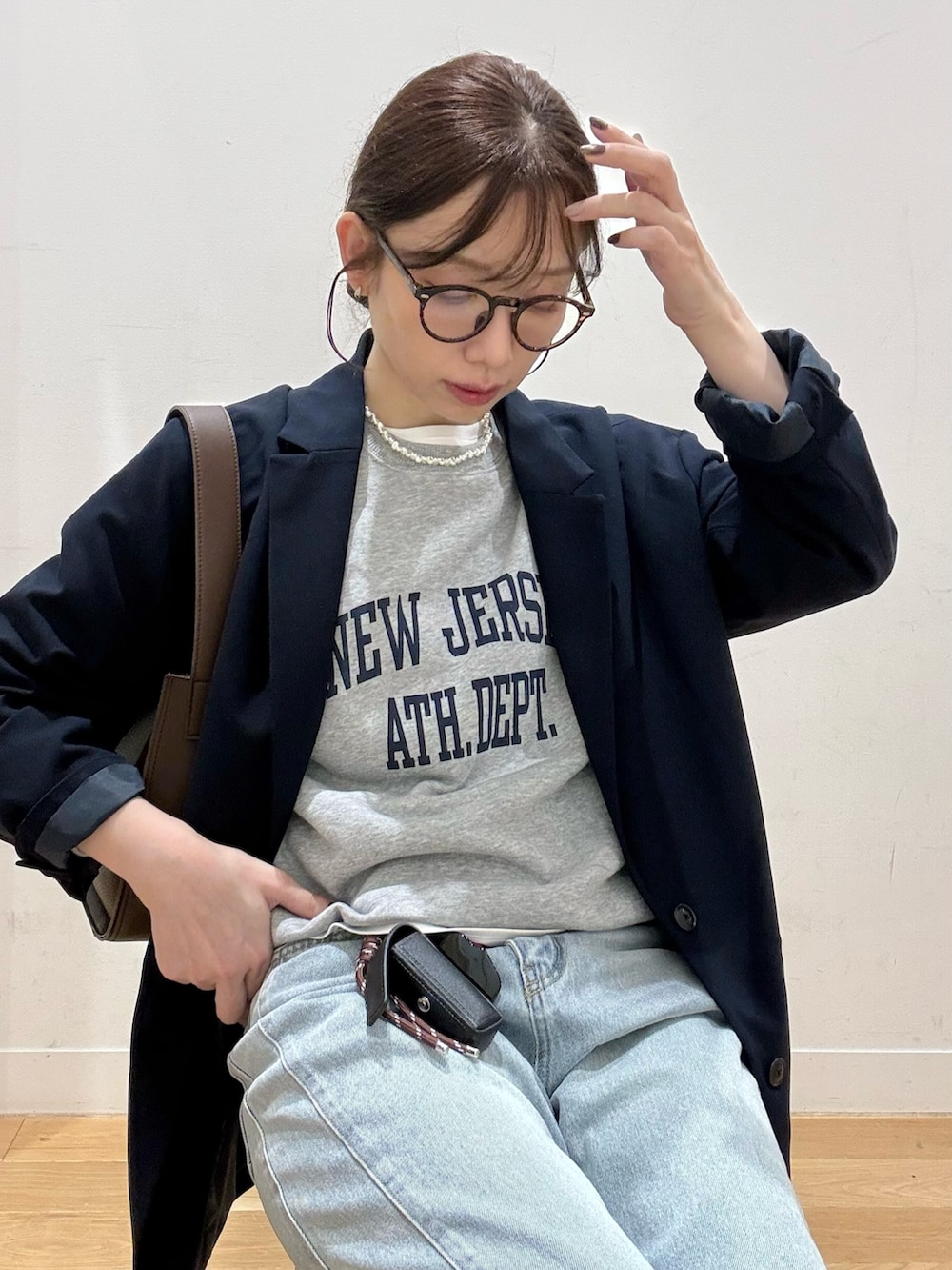 ブラウン系のハンドバッグ、ブルー系のデニムパンツ、ホワイト系のTシャツ/カットソーを着用したレディースの秋コーディネートの4枚目の写真