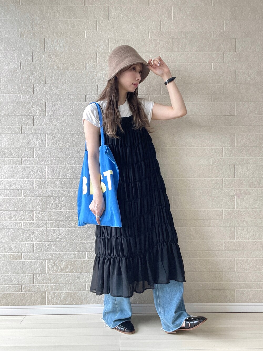 ブラック系のワンピース、ブルー系のトートバッグ、ブルー系のデニムパンツを着用したレディースの夏コーディネートの3枚目の写真