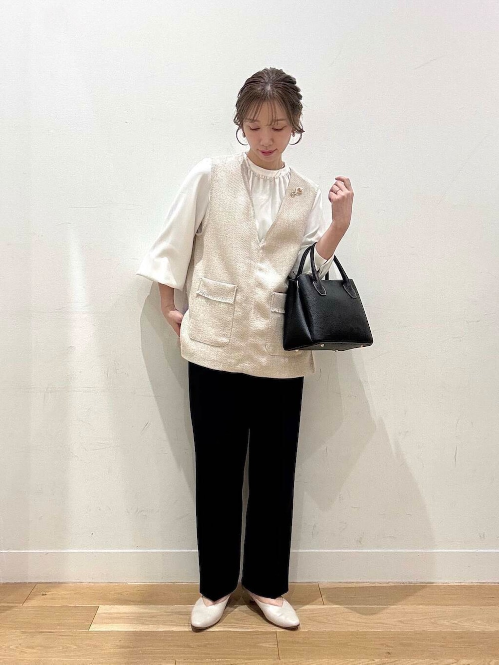 ブラック系のショルダーバッグ、ベージュ系のベスト、グレー系のスーツジャケットを着用したレディースの春コーディネートの3枚目の写真