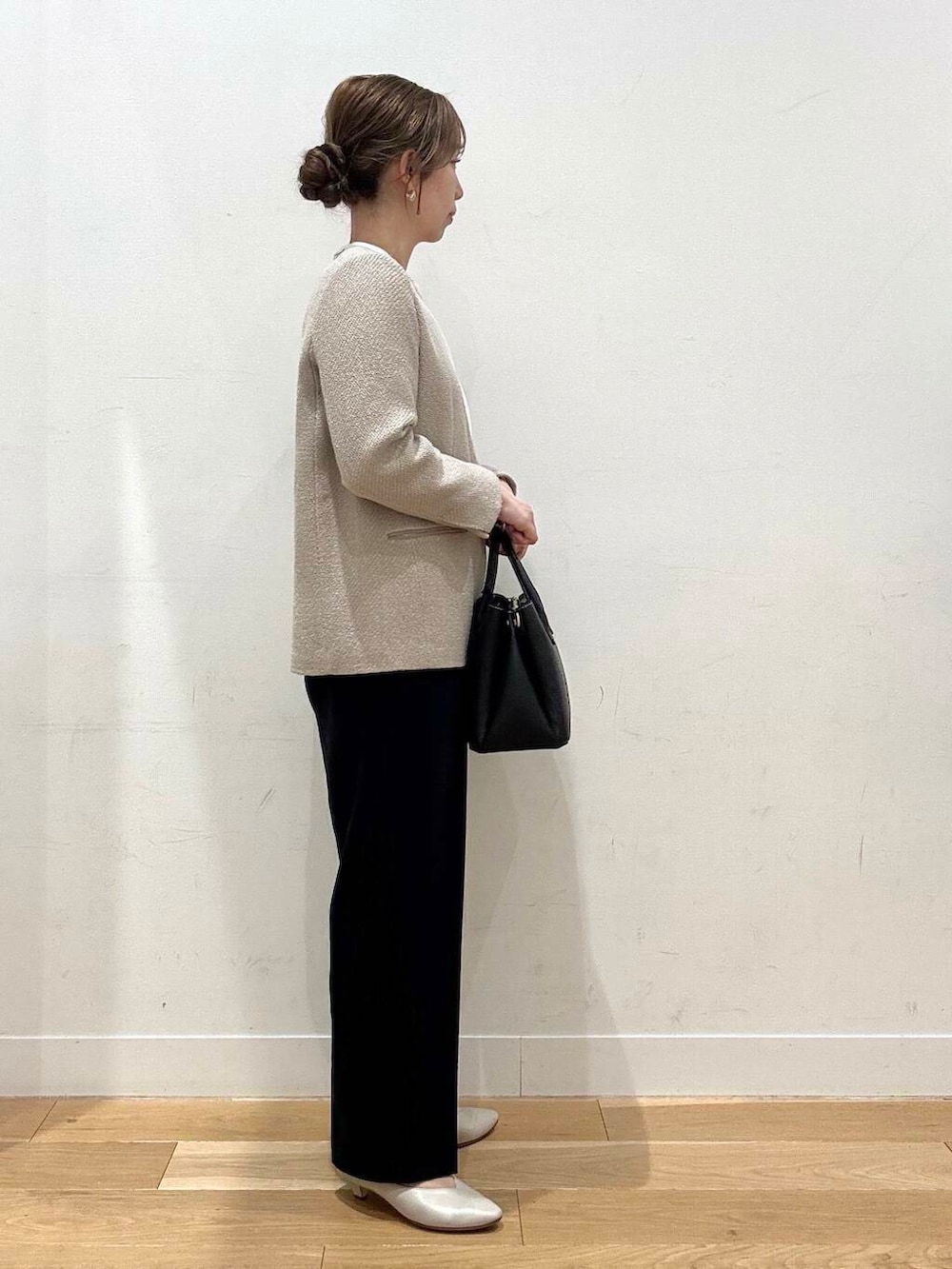 ブラック系のショルダーバッグ、ベージュ系のベスト、グレー系のスーツジャケットを着用したレディースの春コーディネートの5枚目の写真