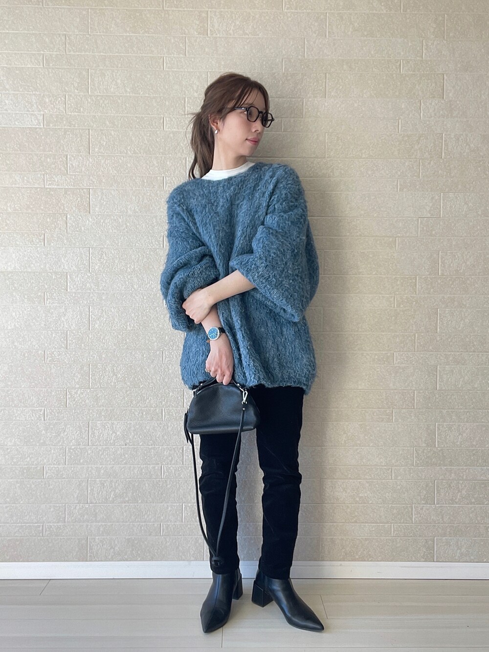 ブラック系のブーツ、ブルー系のニット/セーター、ブラック系のショルダーバッグを着用したレディースの冬コーディネートの2枚目の写真
