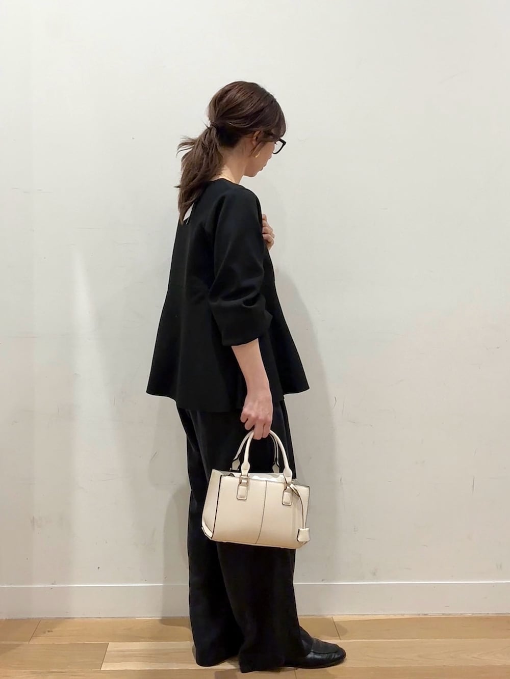 ホワイト系のハンドバッグ、ブラウン系のその他アウター、ブラック系のニット/セーターを着用したレディースの冬コーディネートの8枚目の写真