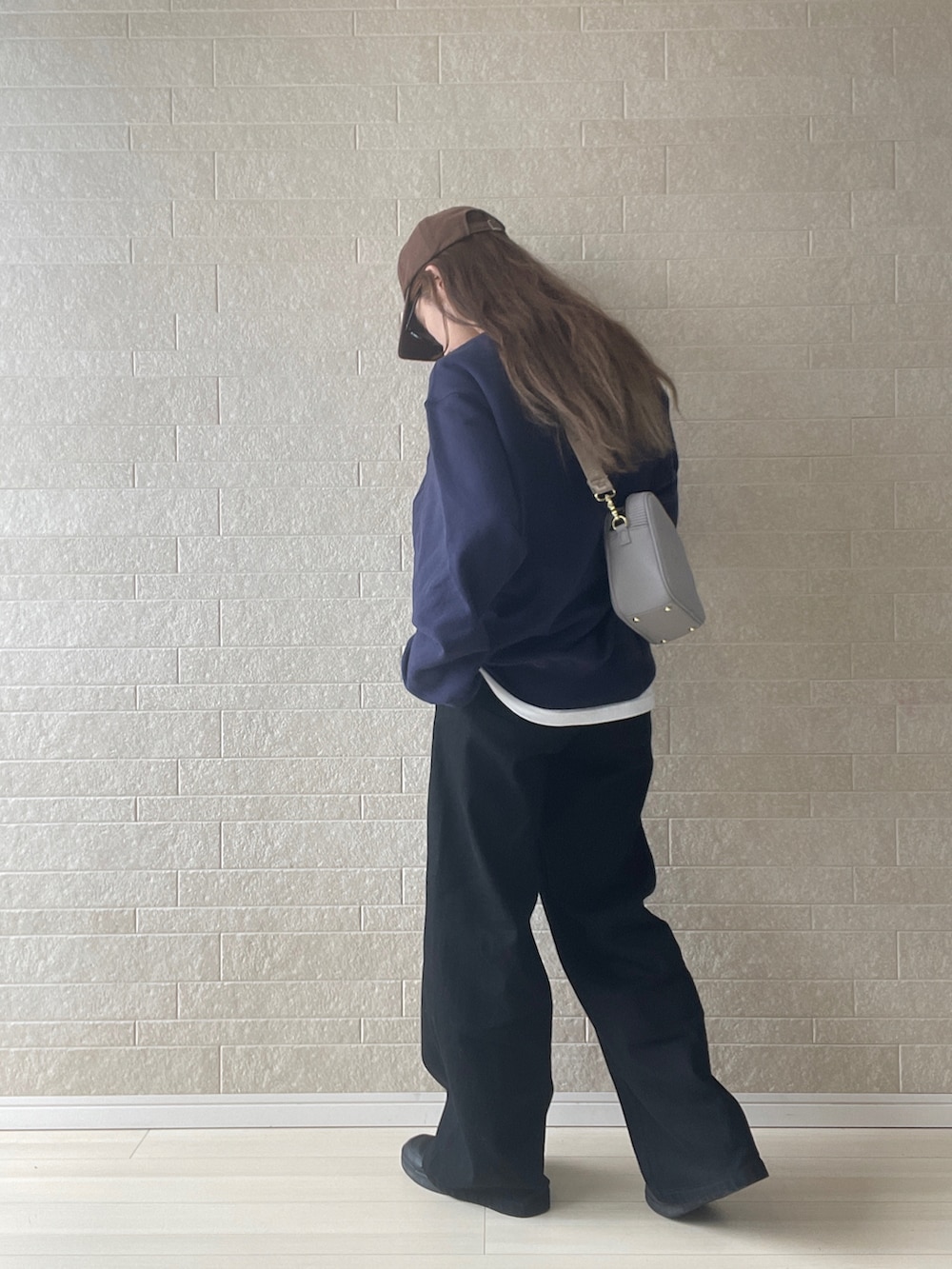 グレー系のショルダーバッグ、ブラック系のデニムパンツ、ホワイト系のTシャツ/カットソーを着用したレディースの秋コーディネートの2枚目の写真