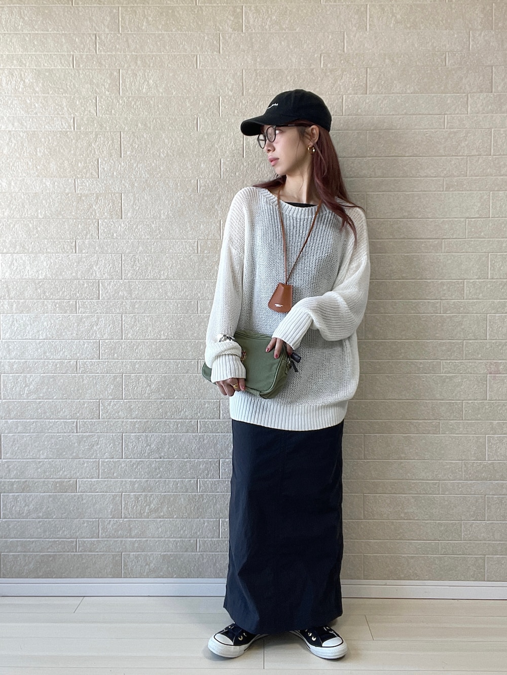 グリーン系のショルダーバッグ、ブラック系のワンピース、ブラック系のスニーカーを着用したレディースの春コーディネートの2枚目の写真