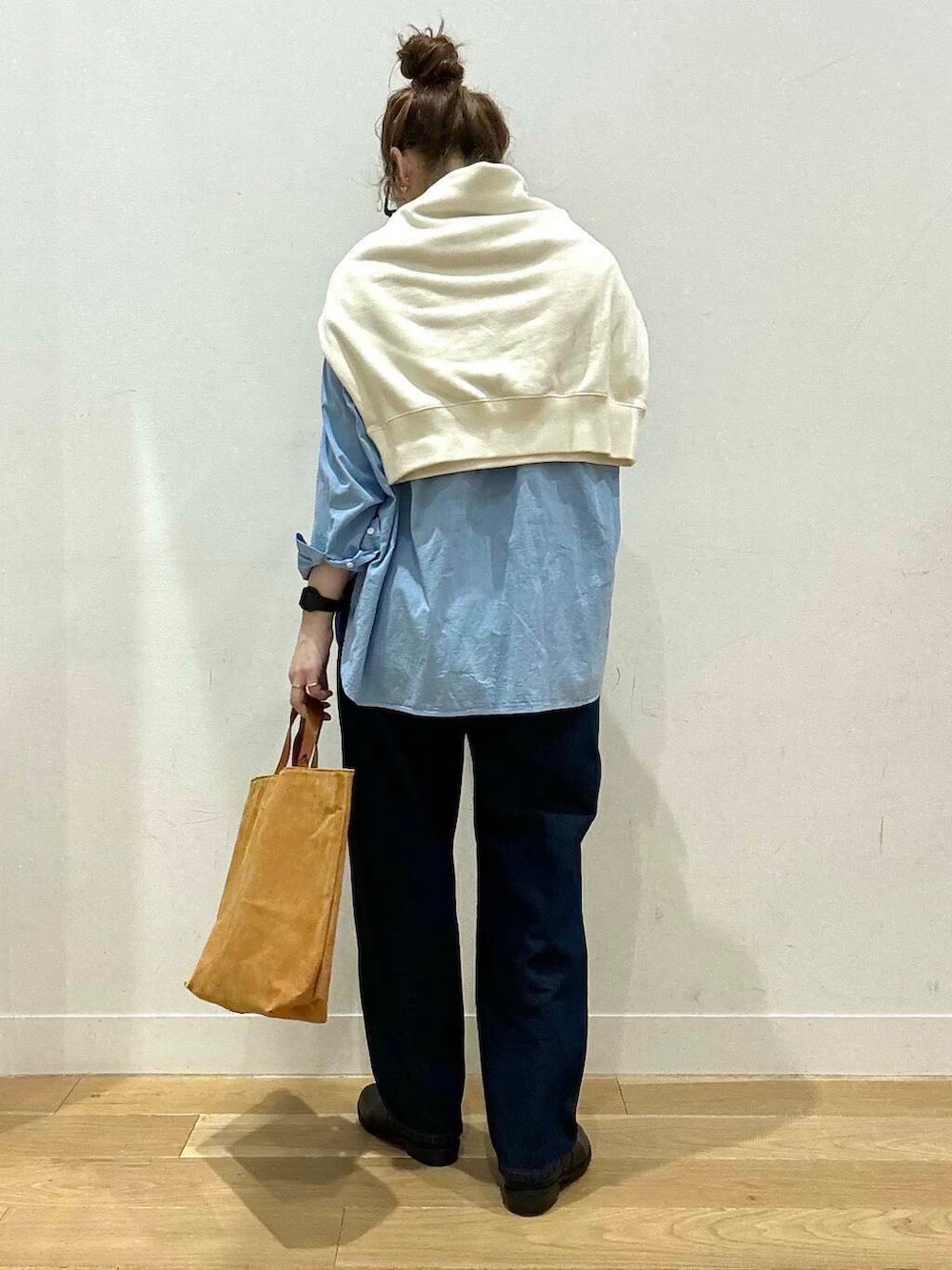 ベージュ系のステンカラーコート、イエロー系のトートバッグ、ブルー系のデニムパンツを着用したレディースの秋コーディネートの7枚目の写真