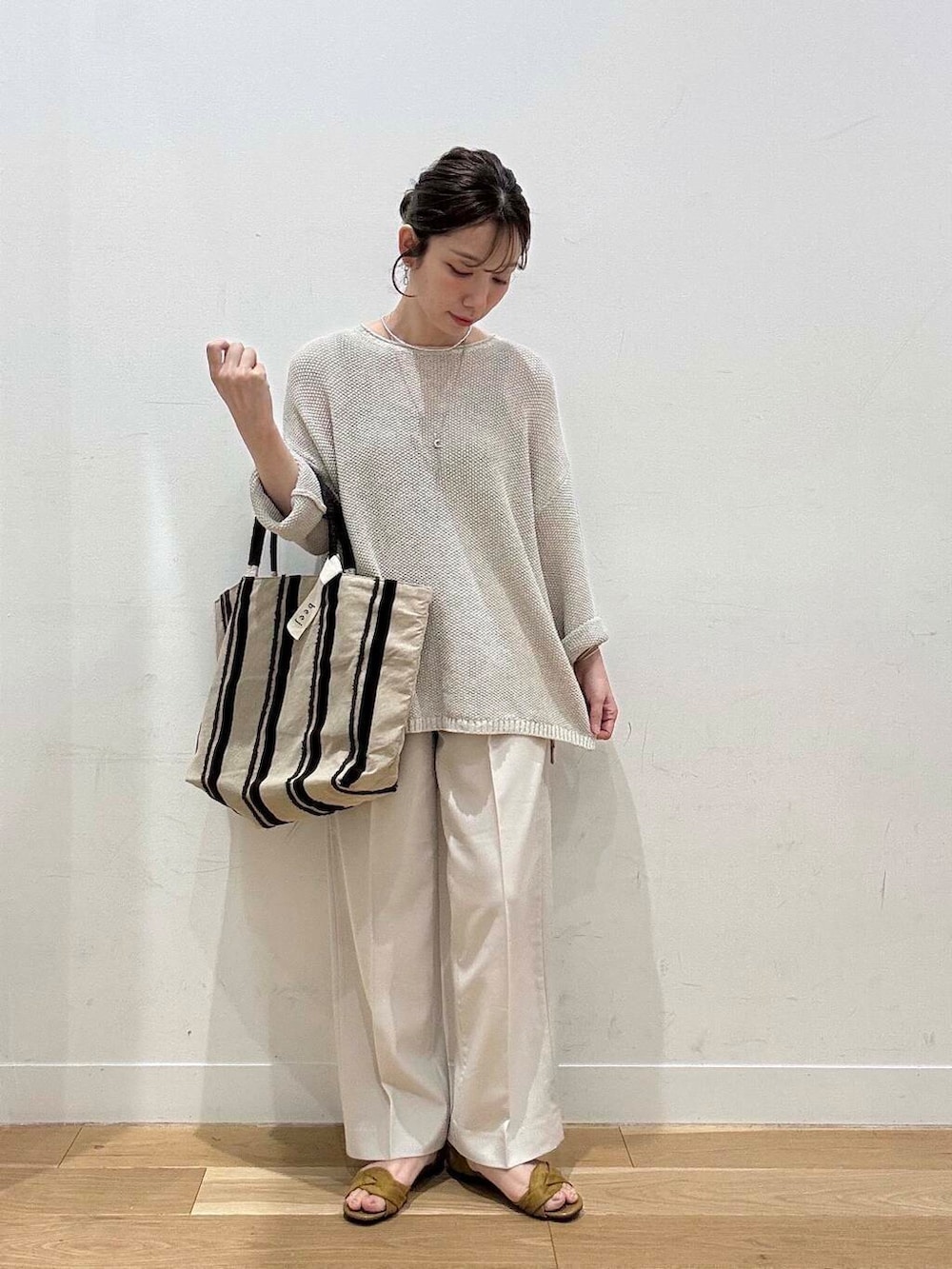 ベージュ系のニット/セーター、イエロー系のサンダル、ブラウン系のトートバッグを着用したレディースの春コーディネートの2枚目の写真