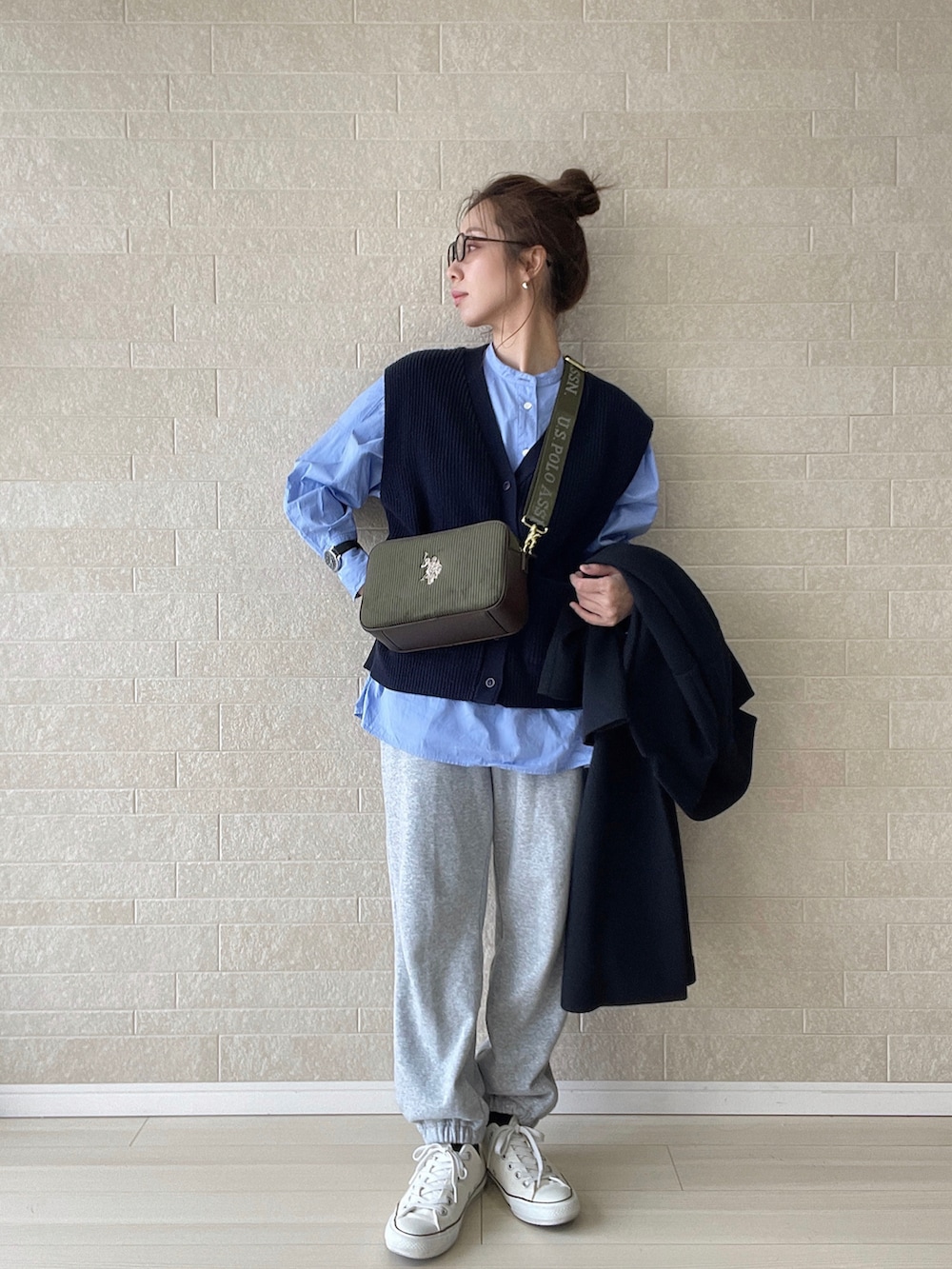 グリーン系のショルダーバッグ、グレー系のスウェットパンツ、ホワイト系のスニーカーを着用したレディースの冬コーディネートの2枚目の写真