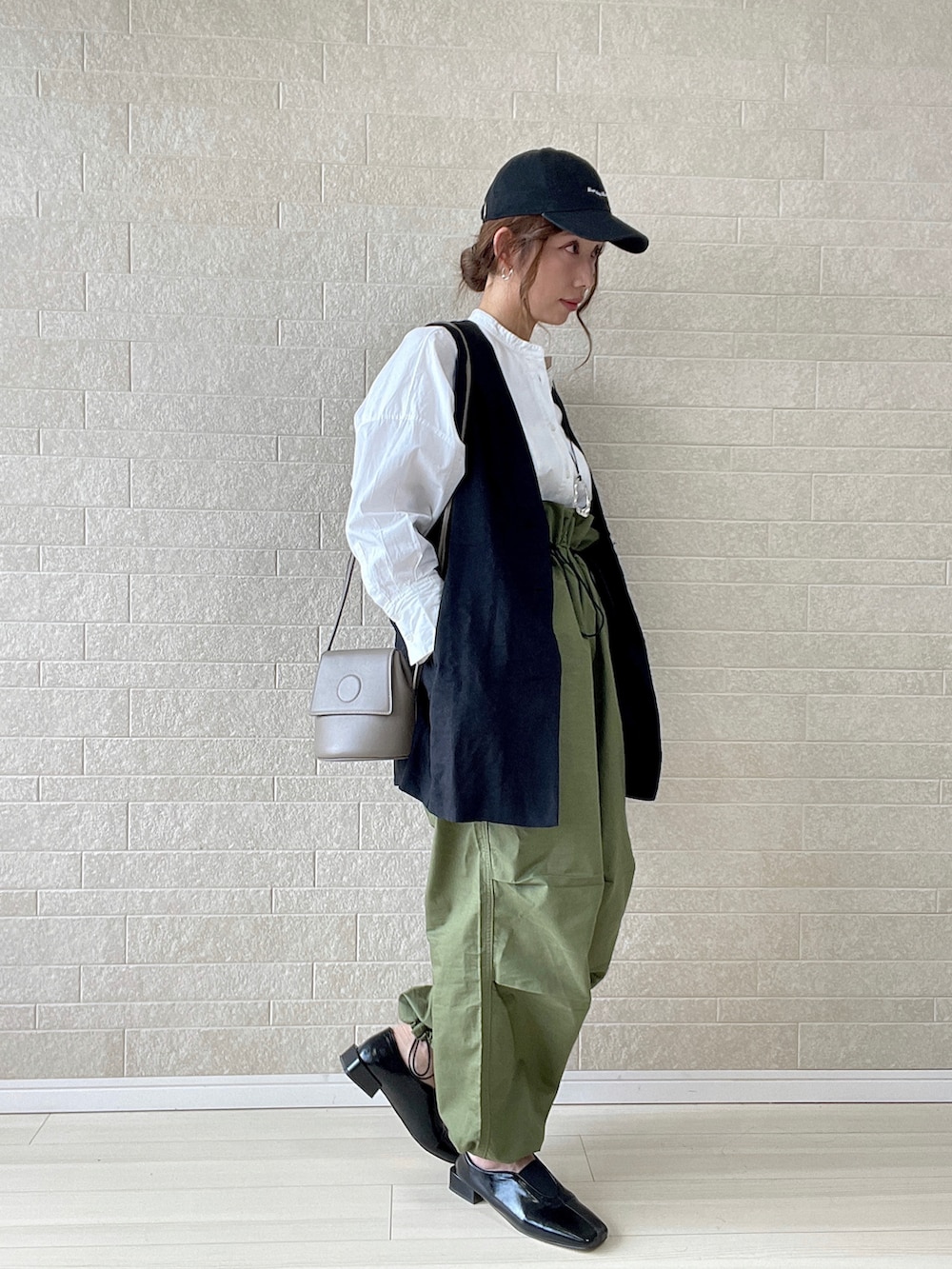 グリーン系のカーゴパンツ、ブラック系のパンプス、グレー系のショルダーバッグを着用したレディースの春コーディネートの2枚目の写真