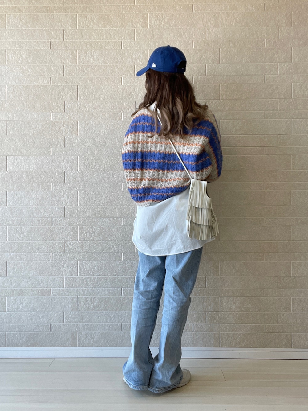 ブルー系のデニムパンツ、ホワイト系のシャツ/ブラウス、ホワイト系のスニーカーを着用したレディースの秋コーディネートの3枚目の写真