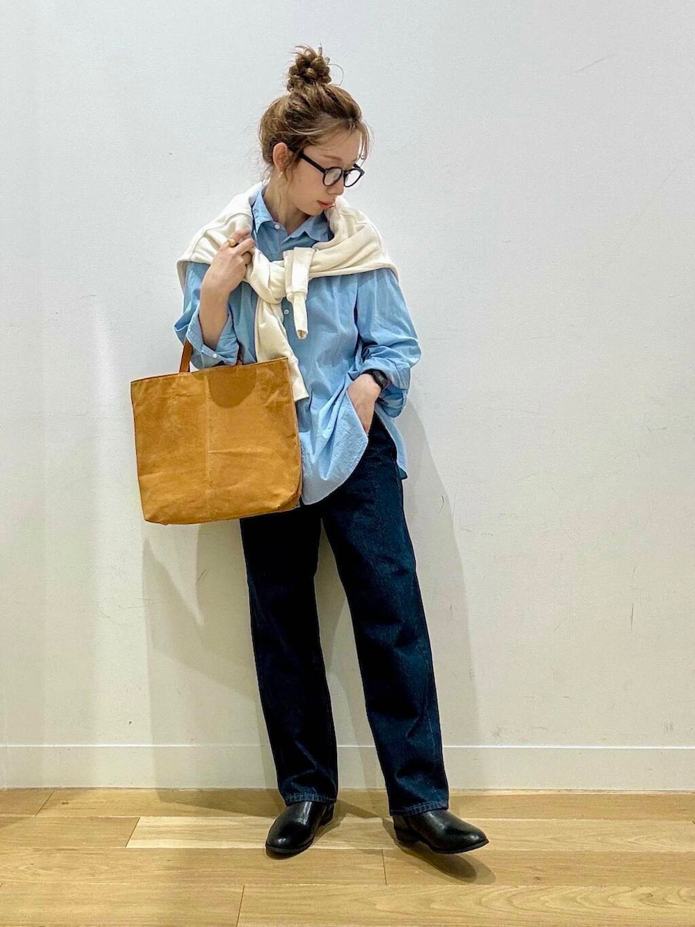 ベージュ系のステンカラーコート、イエロー系のトートバッグ、ブルー系のデニムパンツを着用したレディースの秋コーディネートの8枚目の写真