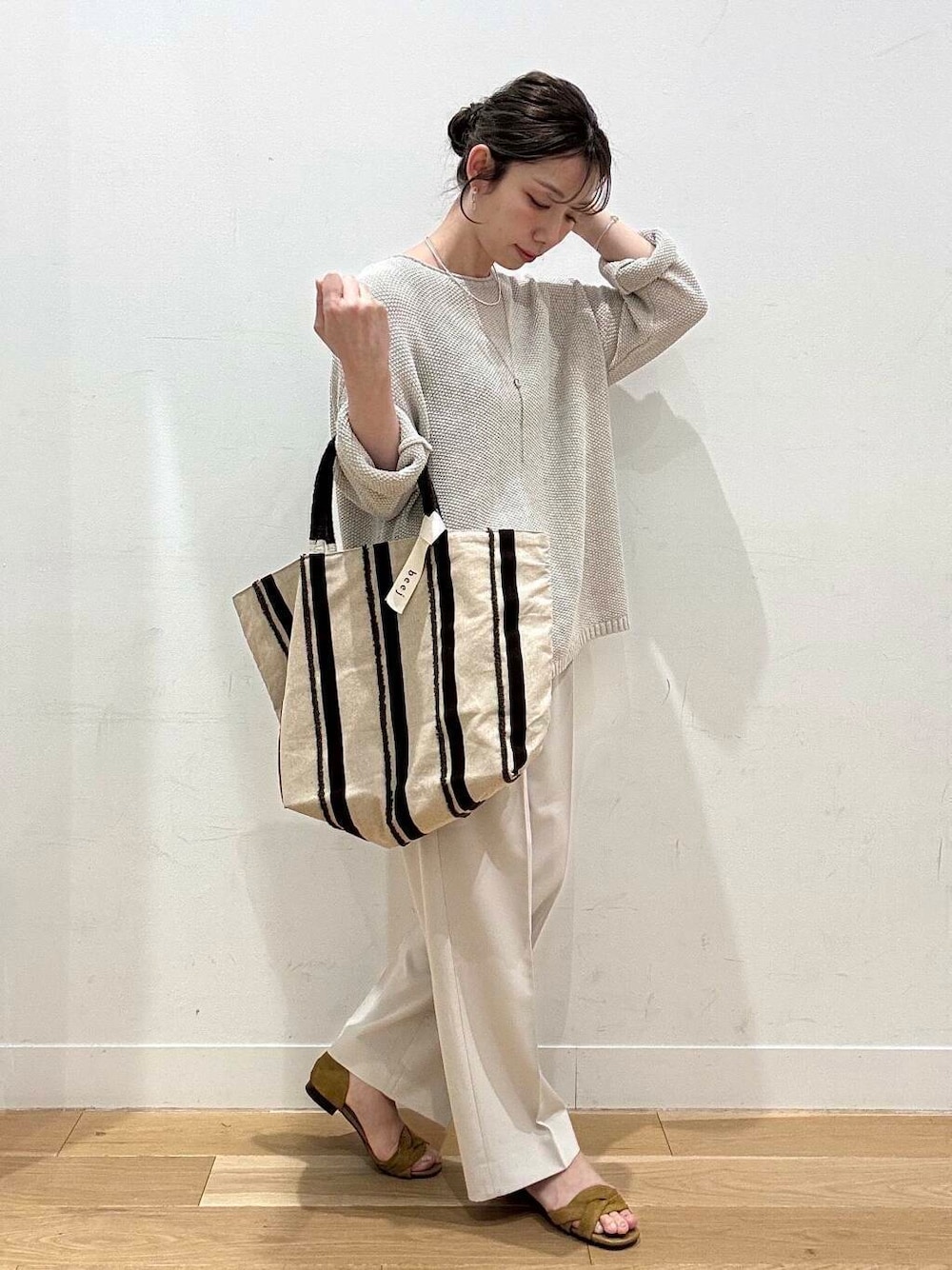 ベージュ系のニット/セーター、イエロー系のサンダル、ブラウン系のトートバッグを着用したレディースの春コーディネートの3枚目の写真