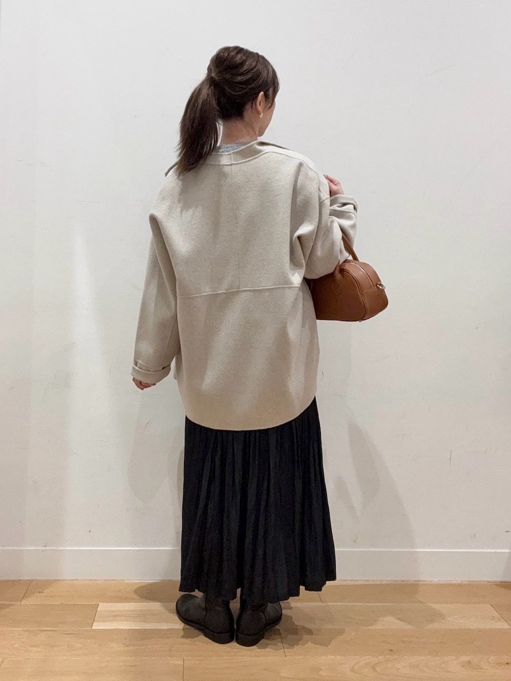 ブラウン系のショルダーバッグ、ブラック系のブーツ、ブラック系のスカートを着用したレディースの秋コーディネートの3枚目の写真