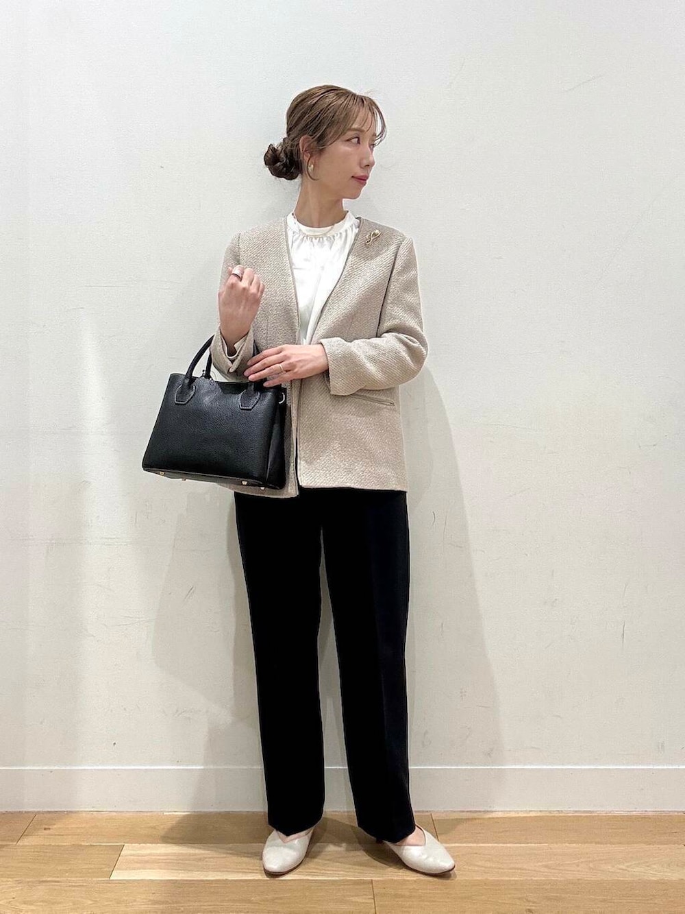 ブラック系のショルダーバッグ、ベージュ系のベスト、グレー系のスーツジャケットを着用したレディースの春コーディネートの4枚目の写真
