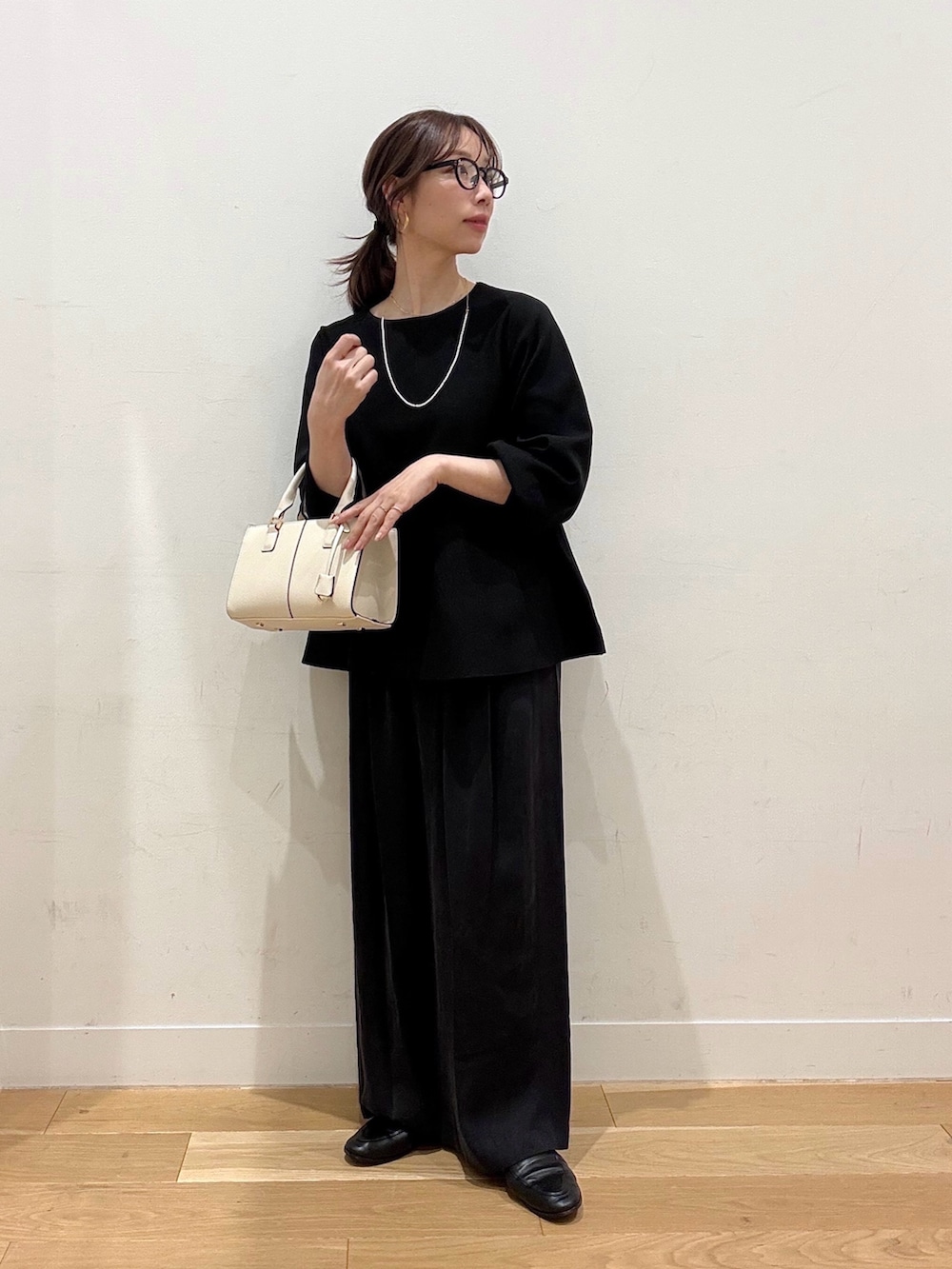 ホワイト系のハンドバッグ、ブラウン系のその他アウター、ブラック系のニット/セーターを着用したレディースの冬コーディネートの5枚目の写真