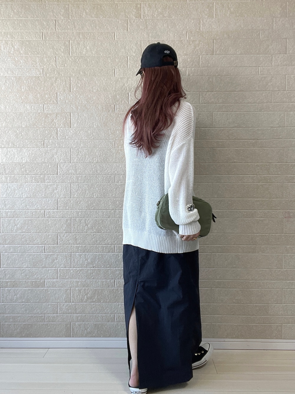 グリーン系のショルダーバッグ、ブラック系のワンピース、ブラック系のスニーカーを着用したレディースの春コーディネートの3枚目の写真