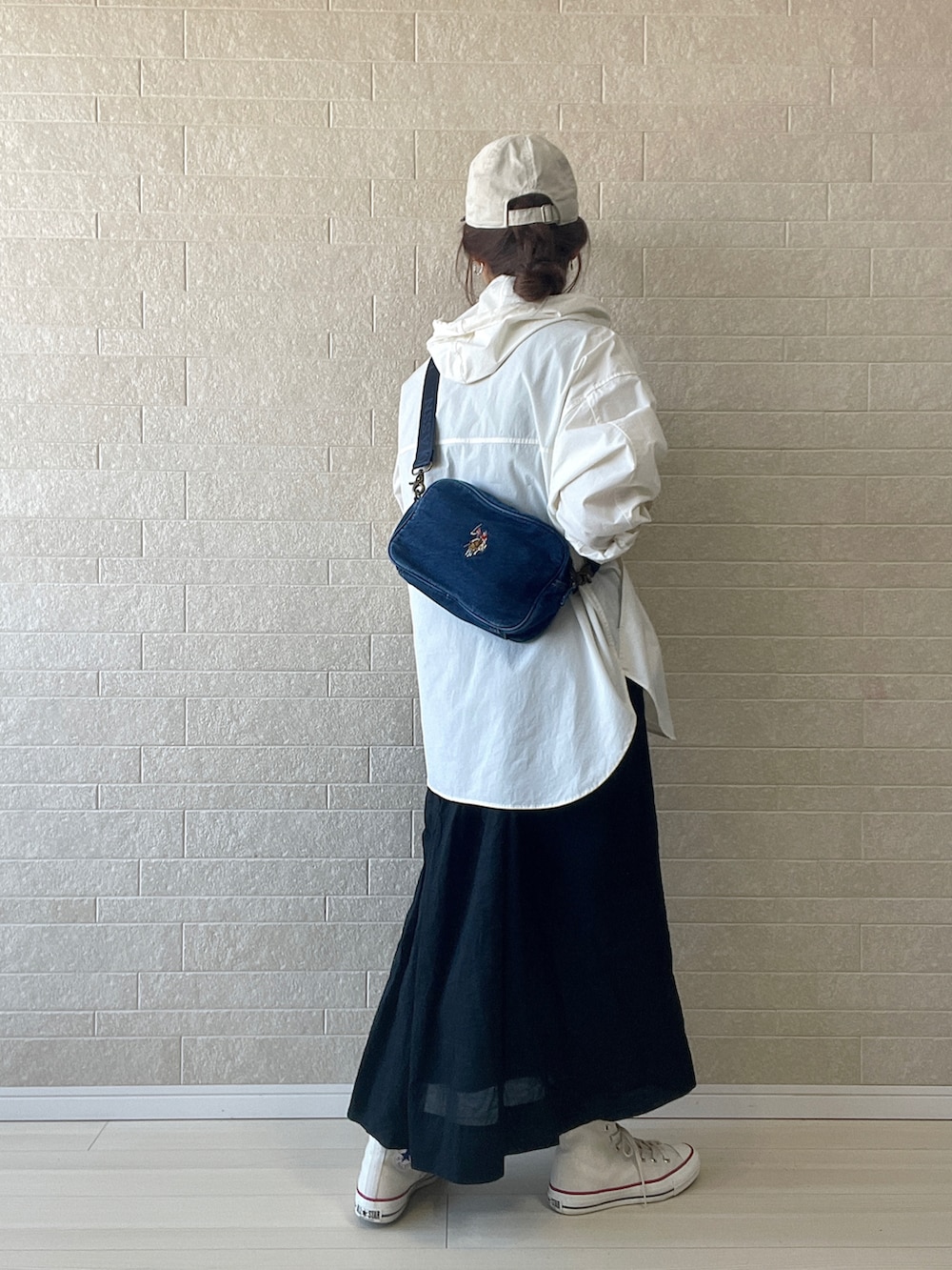 ブルー系のショルダーバッグ、ホワイト系のマウンテンパーカー、ホワイト系のスニーカーを着用したレディースの春コーディネートの3枚目の写真