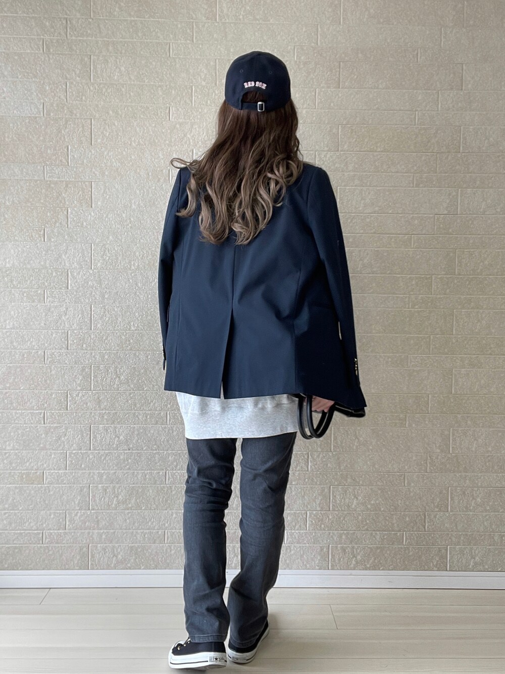 グレー系のデニムパンツ、ブルー系のテーラードジャケット、ブラック系のスニーカーを着用したレディースの冬コーディネートの3枚目の写真