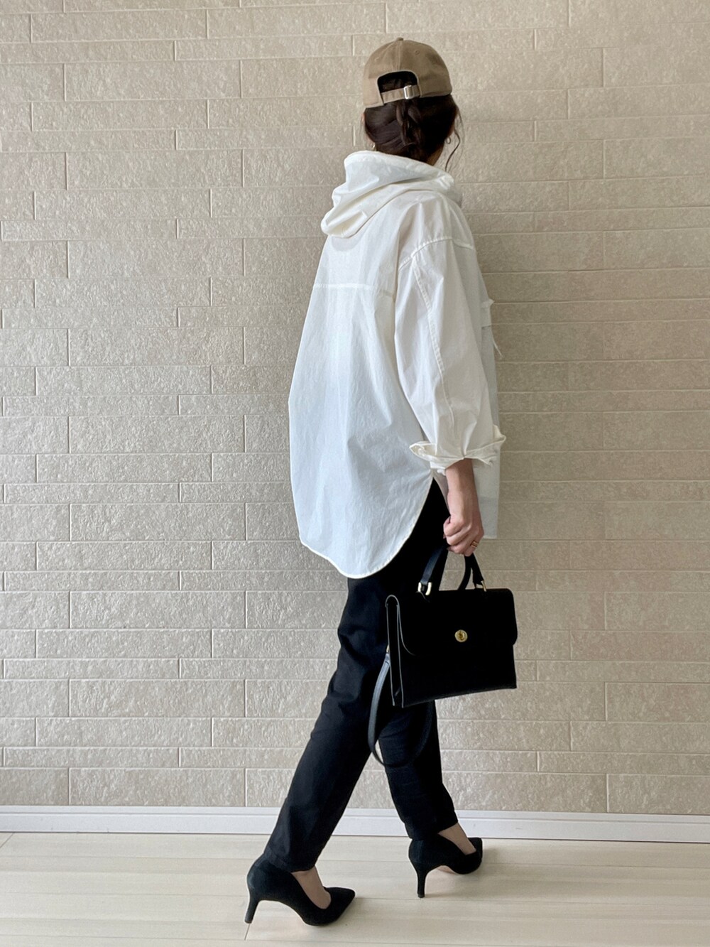 ブラック系のデニムパンツ、ホワイト系のマウンテンパーカー、ブラック系のショルダーバッグを着用したレディースの春コーディネートの3枚目の写真