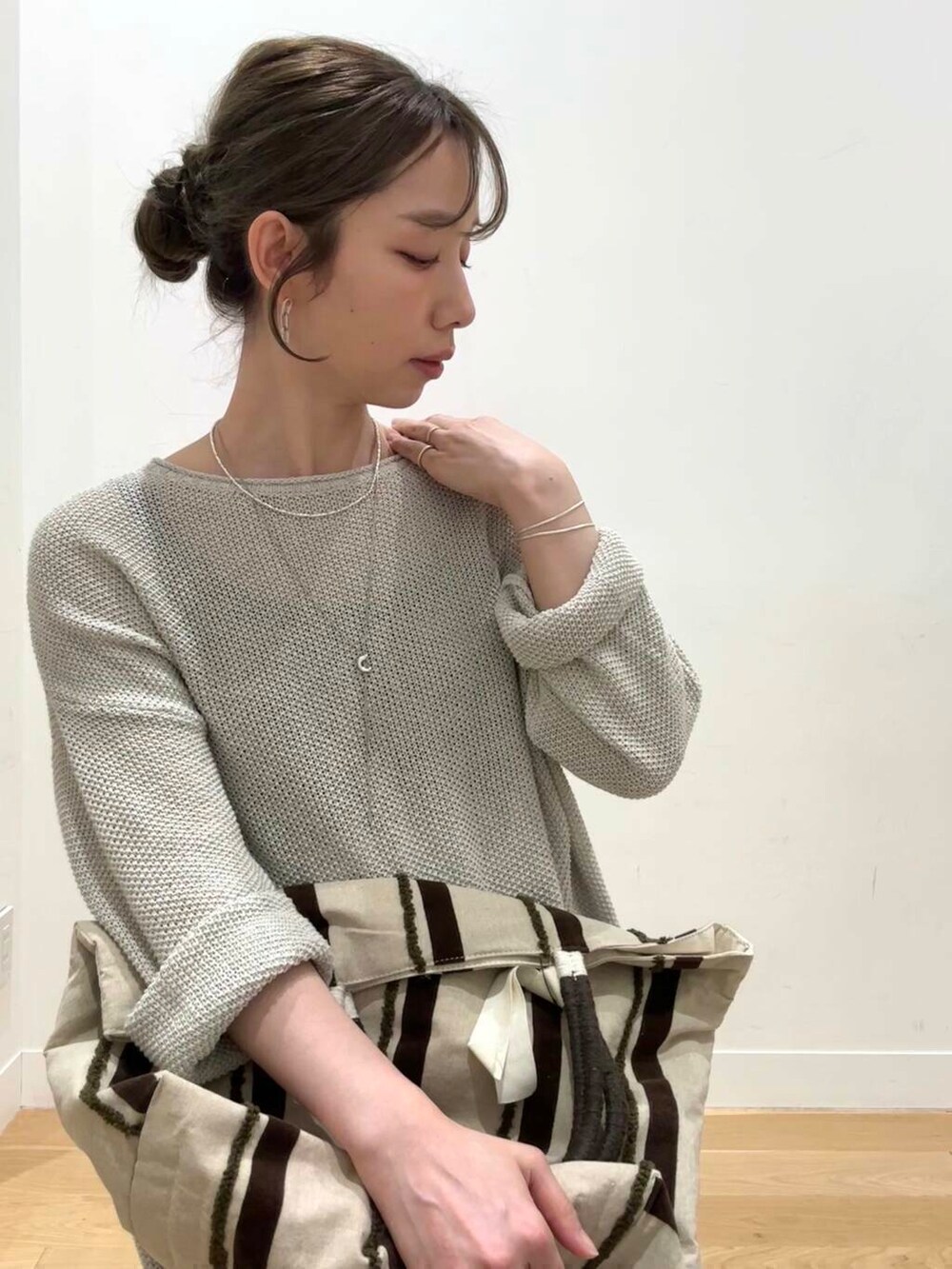 ベージュ系のニット/セーター、イエロー系のサンダル、ブラウン系のトートバッグを着用したレディースの春コーディネートの7枚目の写真