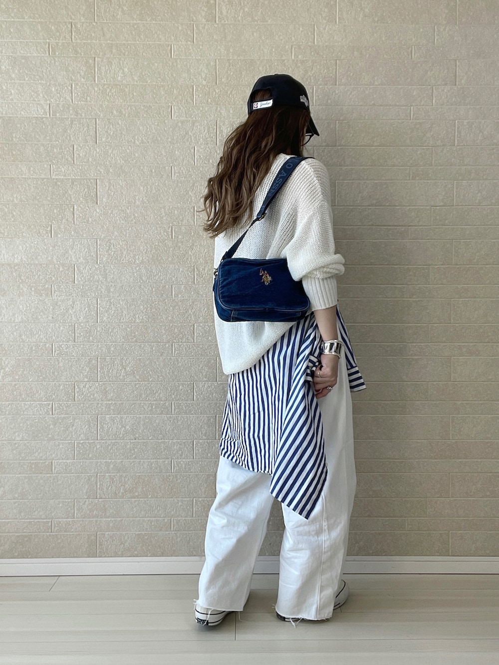 ブルー系のショルダーバッグ、ホワイト系のデニムパンツ、ホワイト系のスニーカーを着用したレディースの春コーディネートの3枚目の写真
