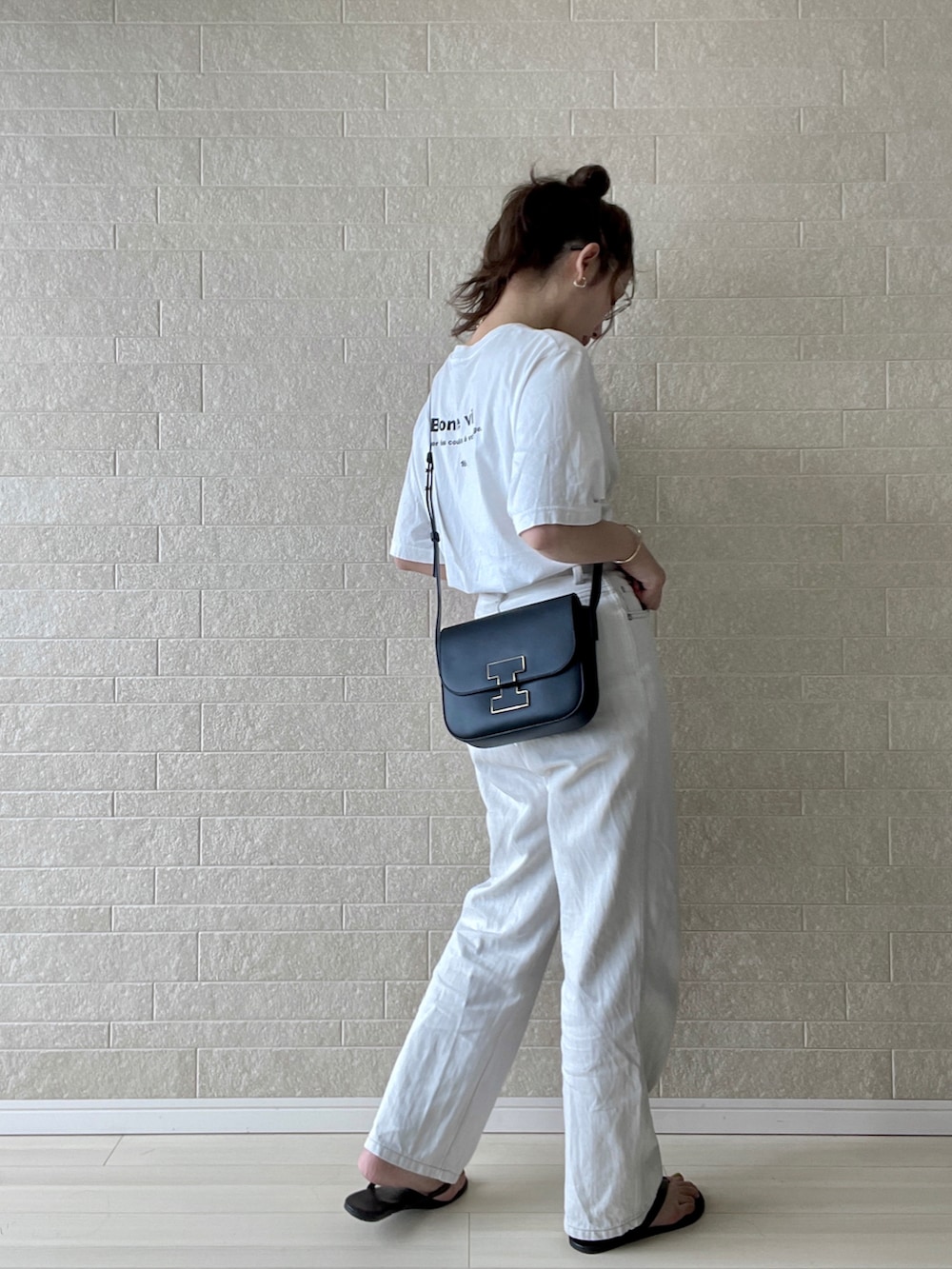 ホワイト系のデニムパンツ、ブラック系のショルダーバッグ、ホワイト系のTシャツ/カットソーを着用したレディースの夏コーディネートの3枚目の写真