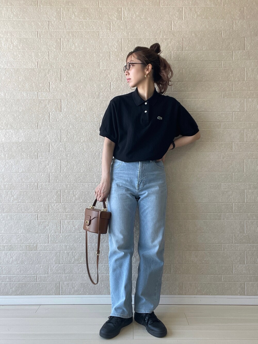ブルー系のデニムパンツ、ブラック系のポロシャツ、ブラック系のスニーカーを着用したレディースの夏コーディネートの2枚目の写真