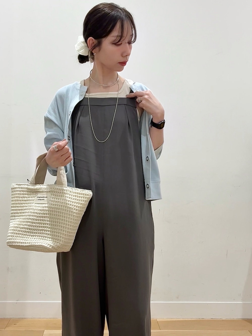 ホワイト系のトートバッグ、ブルー系のカーディガン/ボレロ、ホワイト系のタンクトップを着用したレディースの春コーディネートの6枚目の写真