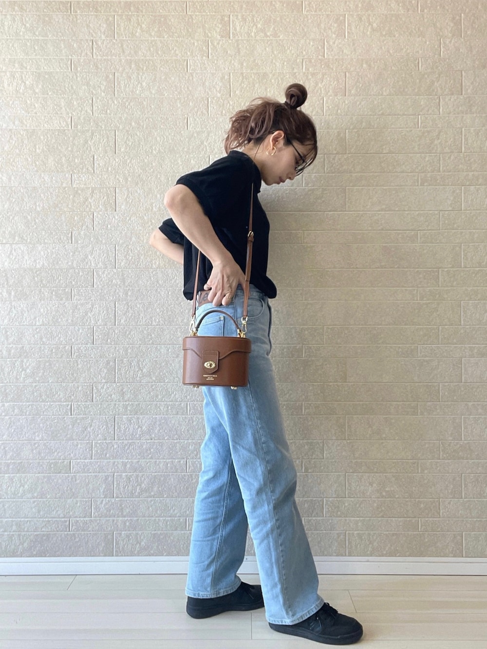 ブルー系のデニムパンツ、ブラック系のポロシャツ、ブラック系のスニーカーを着用したレディースの夏コーディネートの3枚目の写真