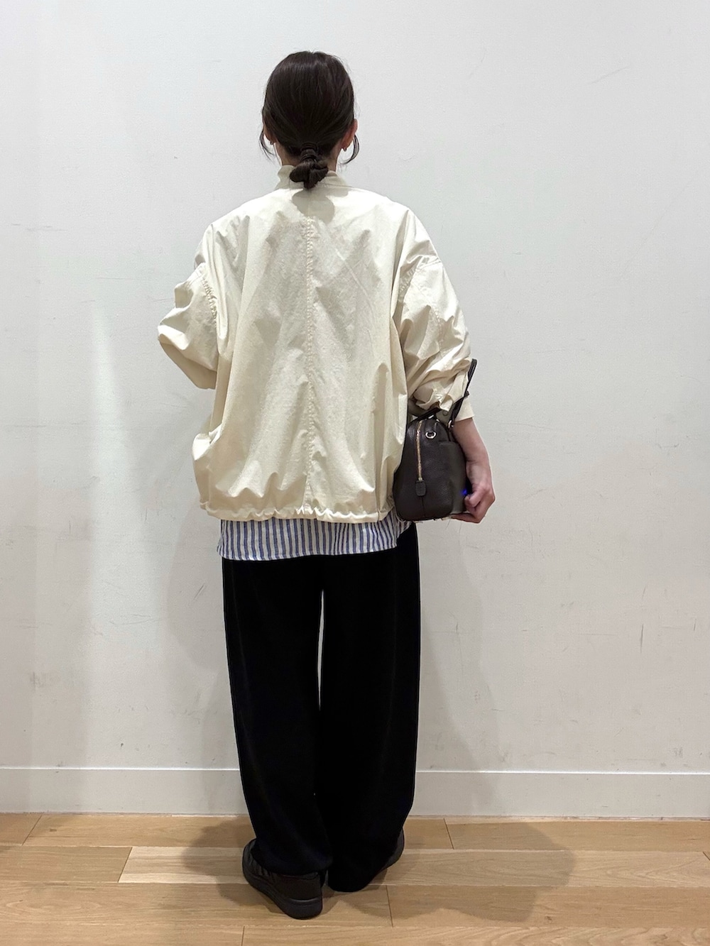 ホワイト系のブルゾン、ブラウン系のボストンバッグ、ブラック系のその他パンツを着用したレディースの春コーディネートの7枚目の写真