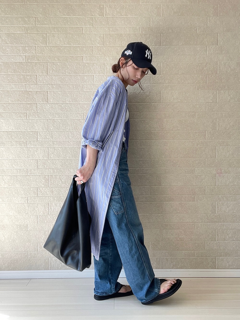 ブルー系のデニムパンツ、ホワイト系のTシャツ/カットソー、ブラック系のトートバッグを着用したレディースの春コーディネートの4枚目の写真