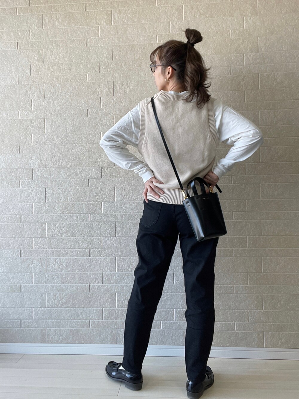 ブラック系のデニムパンツ、ベージュ系のベスト、ホワイト系のTシャツ/カットソーを着用したレディースの春コーディネートの4枚目の写真