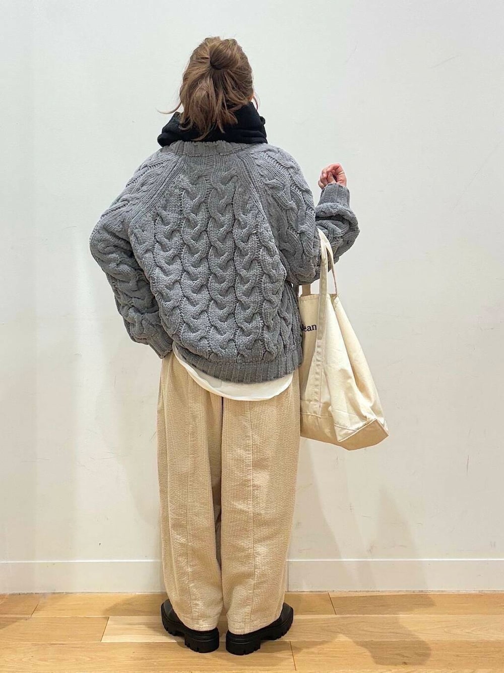 ホワイト系のトートバッグ、ブラック系のブーツ、ホワイト系のTシャツ/カットソーを着用したレディースの冬コーディネートの3枚目の写真