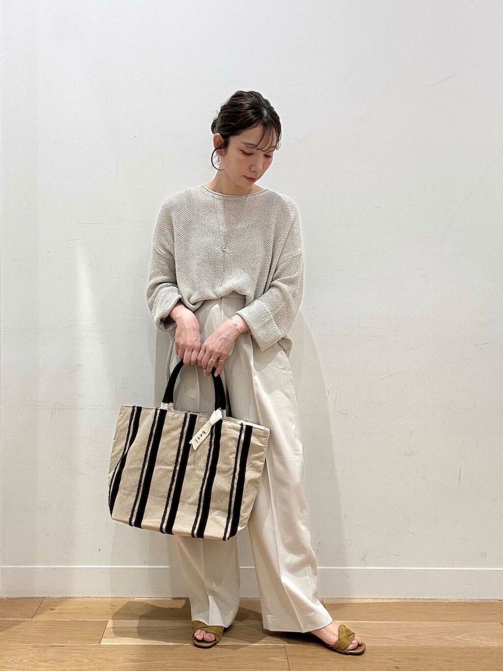 ベージュ系のニット/セーター、イエロー系のサンダル、ブラウン系のトートバッグを着用したレディースの春コーディネートの5枚目の写真