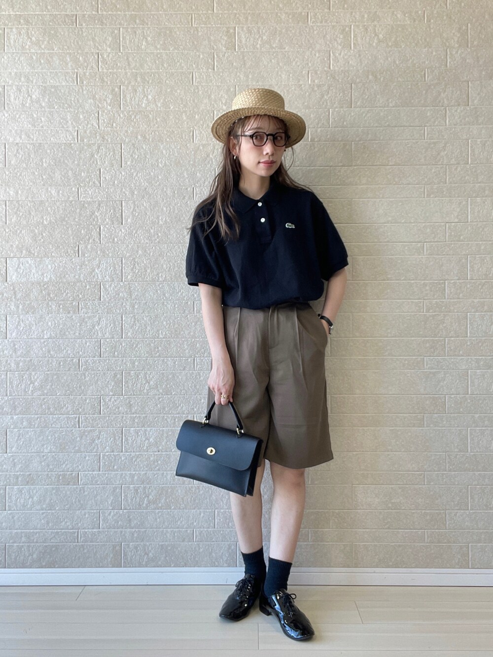 ブラック系のポロシャツ、ブラウン系のその他パンツ、ブラック系のドレスシューズを着用したレディースの夏コーディネートの2枚目の写真