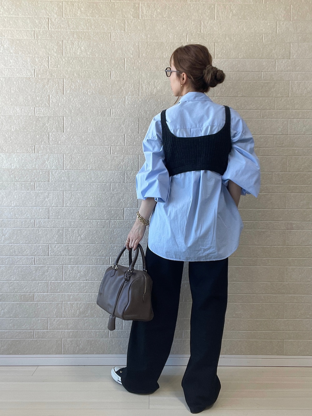 ブラック系のデニムパンツ、グレー系のニット/セーター、ブラウン系のボストンバッグを着用したレディースの秋コーディネートの2枚目の写真