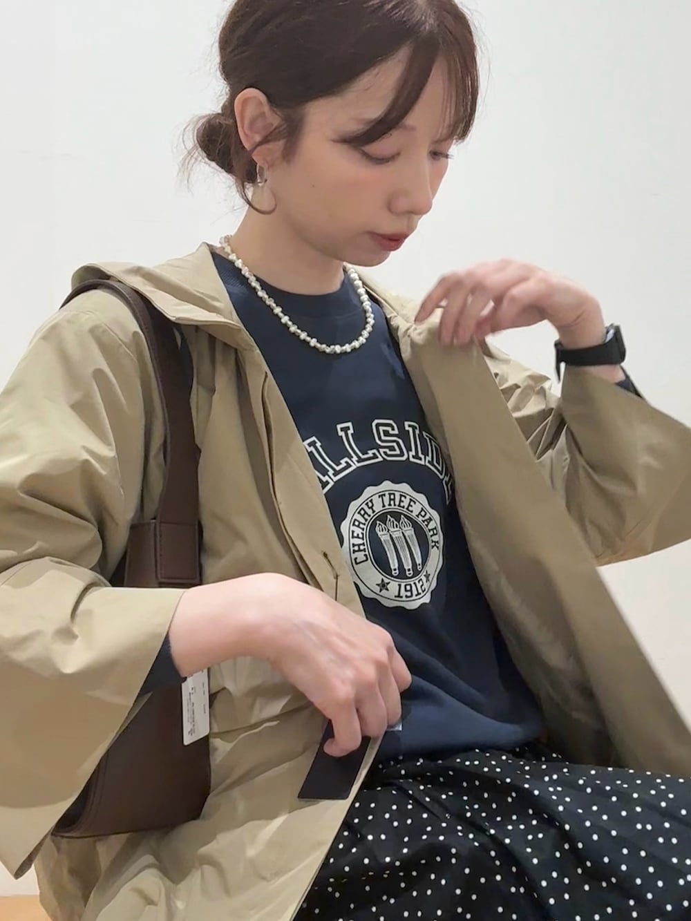 ブラウン系のハンドバッグ、ベージュ系のその他アウター、ブラック系のレインシューズを着用したレディースの秋コーディネートの6枚目の写真
