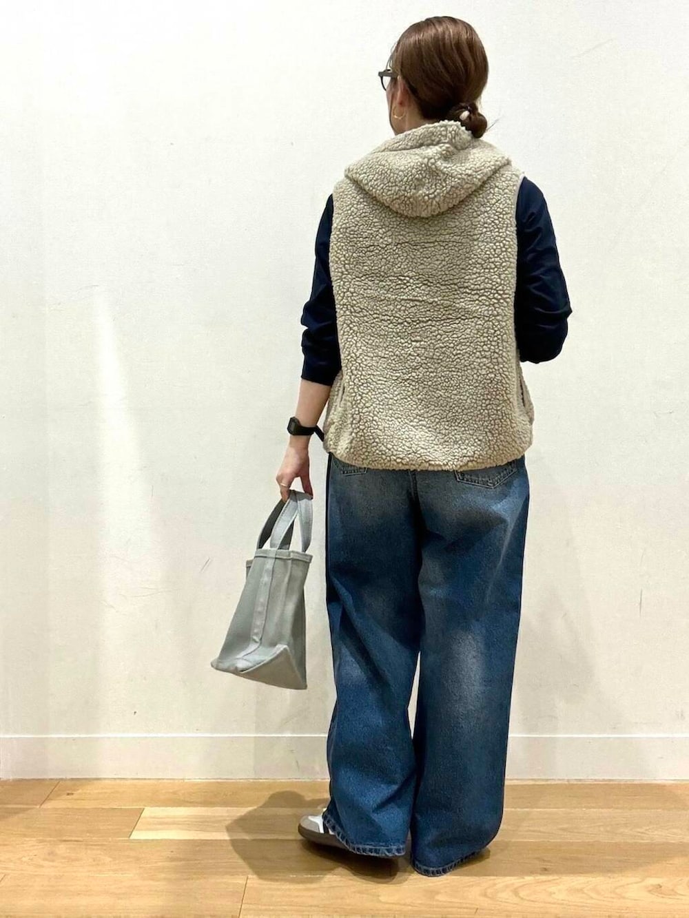 ブルー系のデニムパンツ、ホワイト系のスニーカー、グレー系のトートバッグを着用したレディースの秋コーディネートの4枚目の写真