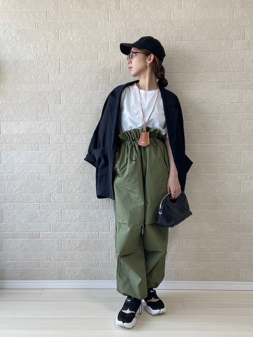 グリーン系のカーゴパンツ、ブラック系のテーラードジャケット、ブラック系のキャップを着用したレディースの春コーディネートの2枚目の写真