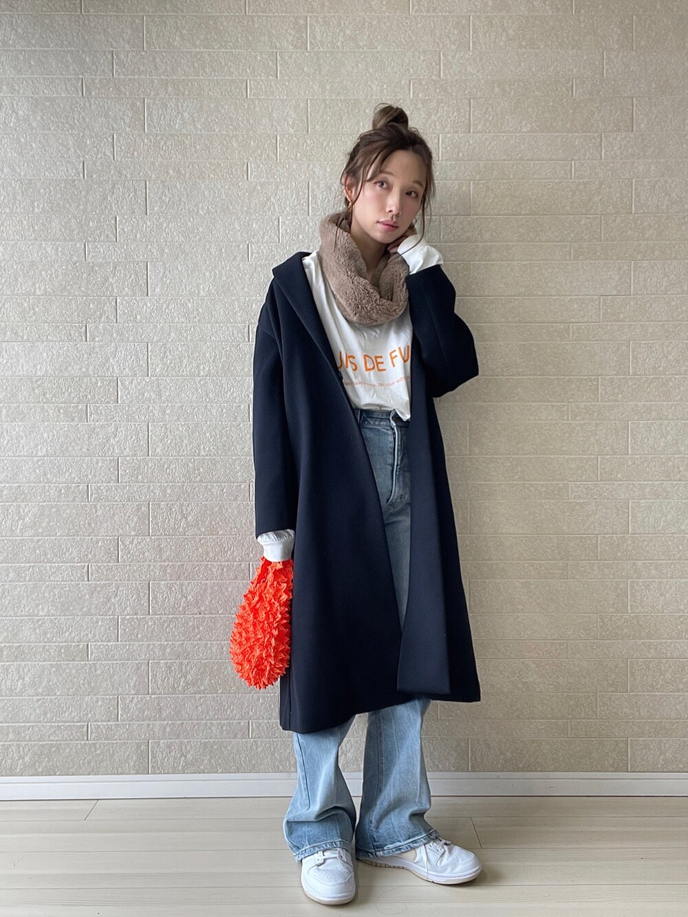 ブルー系のチェスターコート、ブルー系のデニムパンツ、オレンジ系のエコバッグ/サブバッグを着用したレディースの秋コーディネートの3枚目の写真