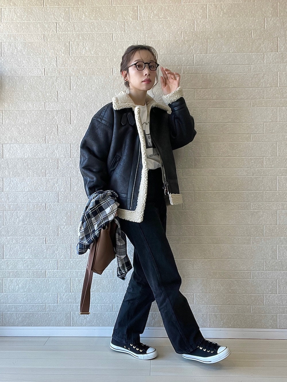 ブラック系のムートンコート、ブラック系のデニムパンツ、ブラウン系のショルダーバッグを着用したレディースの秋コーディネートの5枚目の写真