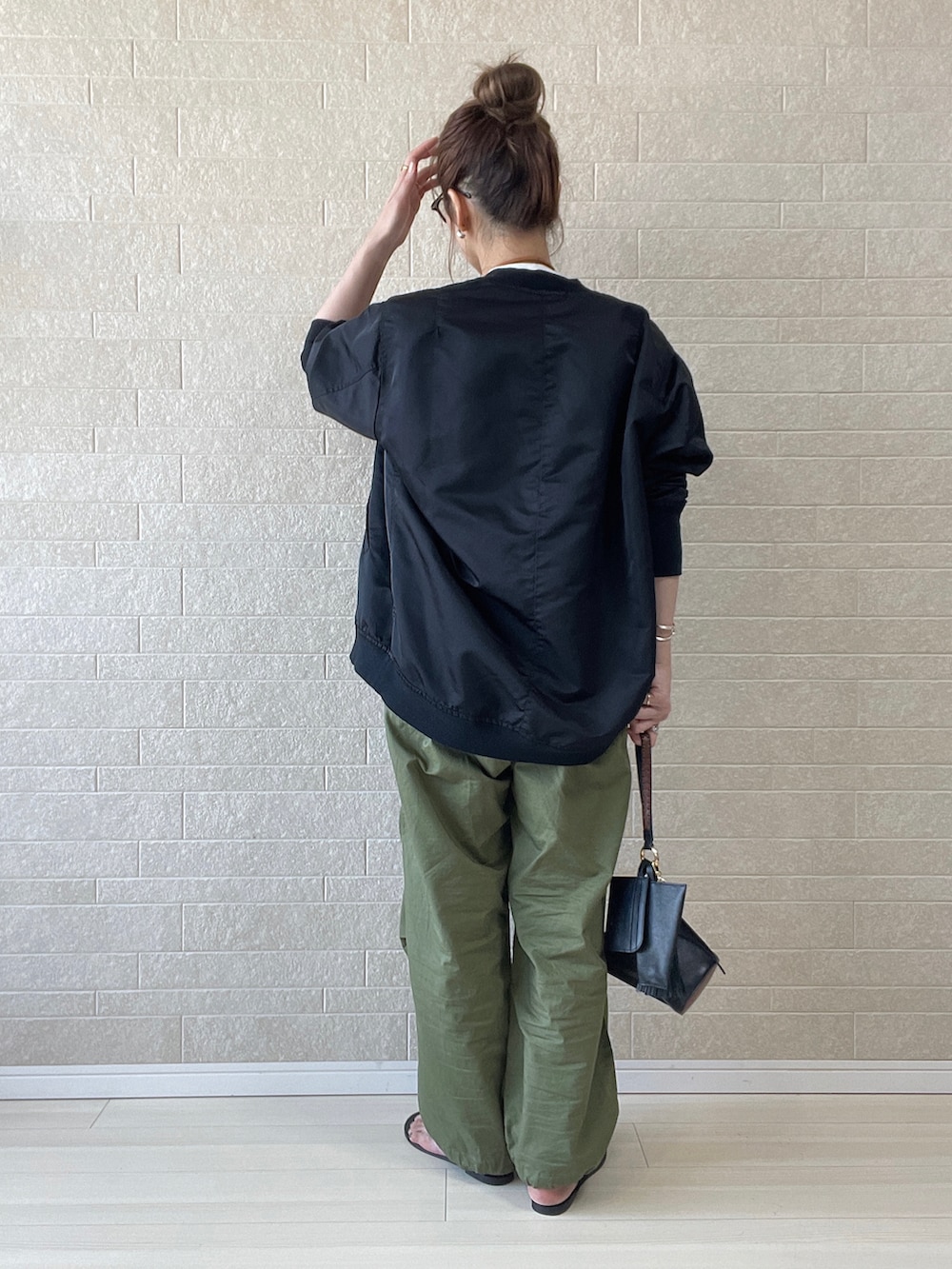 グリーン系のカーゴパンツ、ブラック系のブルゾン、ブラック系のサンダルを着用したレディースの春コーディネートの3枚目の写真