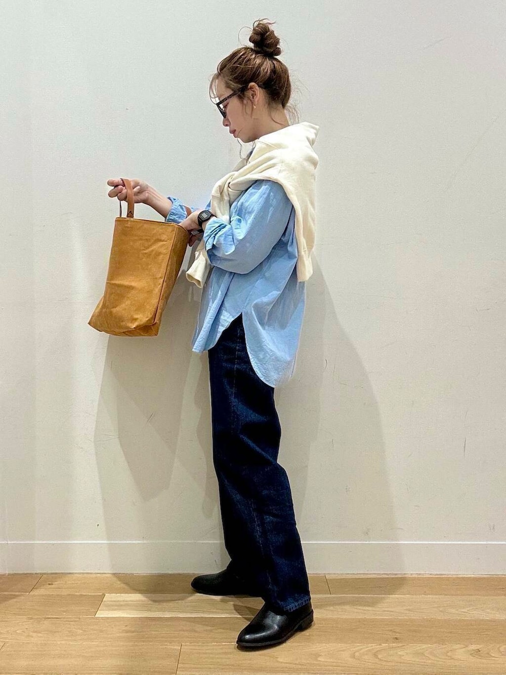 ベージュ系のステンカラーコート、イエロー系のトートバッグ、ブルー系のデニムパンツを着用したレディースの秋コーディネートの6枚目の写真